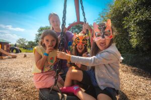girls on a tire swing wearing animal masks at animal planet camp